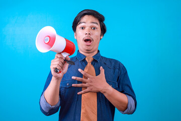 Shocked young Asian man shouting through a megaphone with surprised expression