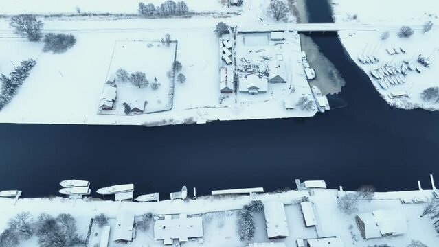 Aerial view south side of the village by the river in winter. The whole environment is covered with a thick layer of snow.