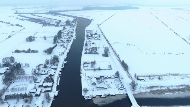 Aerial view The village is located near the river in winter. The house and the surrounding meadows are covered with snow.
