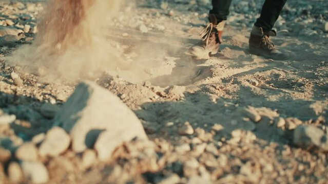 Man digs hole and shovels sandy soil in dry Judean desert, low angle slomo
