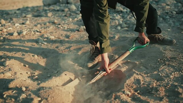 Man use spade to dig hole in sandy desert soil, closeup low angle