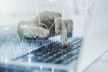 Abstract creative financial graph with hand typing on laptop on background, forex and investment...