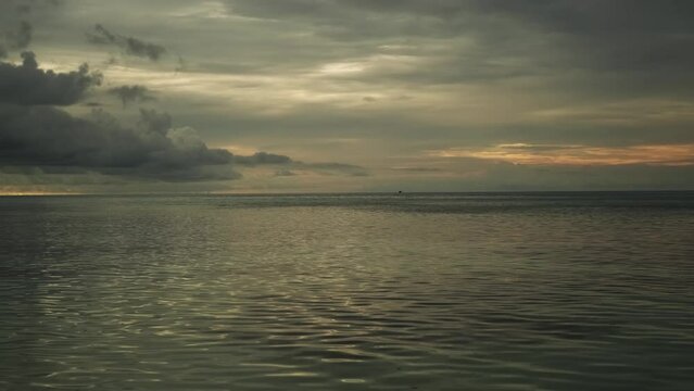Calm waves of the sea during sunset. Beautiful pre-storm cloudy sky on the background.