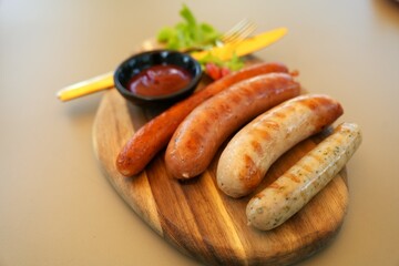 Close up grilled sausages served on wooden cutting board  with  ketchup and fork spoon on side dish , Copy space.