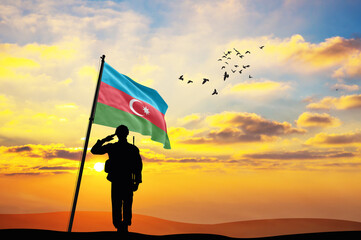 Silhouette of a soldier with the Azerbaijan flag stands against the background of a sunset or...