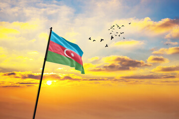 Waving flag of Azerbaijan against the background of a sunset or sunrise. Azerbaijan flag for Independence Day. The symbol of the state on wavy fabric.