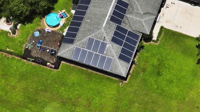 Aerial view of typical American building roof with rows of blue solar photovoltaic panels for producing clean ecological electric energy. Renewable electricity with zero emission concept