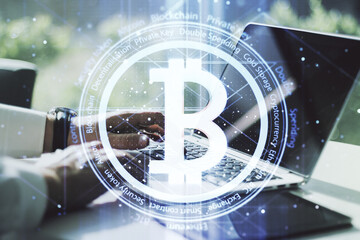 Double exposure of creative Bitcoin symbol with hands typing on laptop on background....