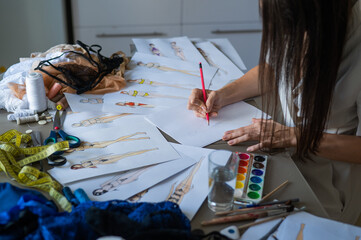 Obraz premium Woman draws sketches of swimwear with a pencil. 