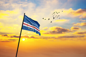 Waving flag of Cabo Verde against the background of a sunset or sunrise. Cabo Verde flag for...