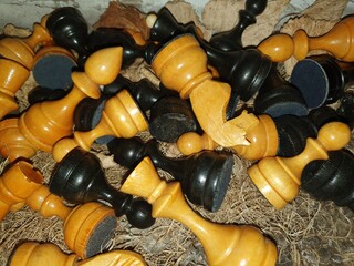 Chess is scattered on dry grass. Wooden chess close-up.