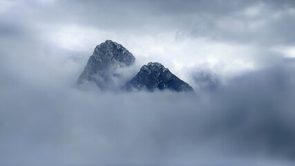 The mountain peak peeks out from the fog. Natural beauty in foggy mountains.