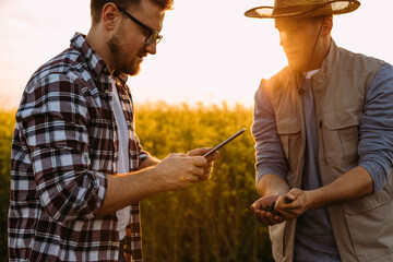 Closeup view of two agronomists inspecting soil with digital tablet.