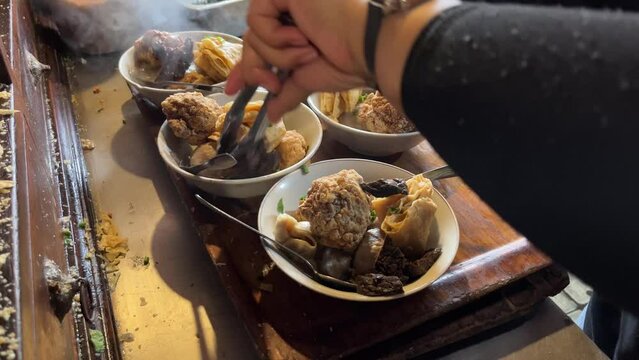 The process of preparing bowls of Indonesian traditional dish named Bakso Malang which is Indonesian meatballs with beef stock