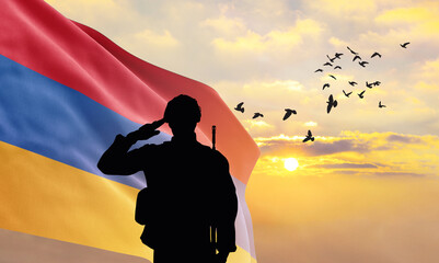 Silhouette of a soldier with the Armenia flag stands against the background of a sunset or sunrise. Concept of national holidays. Commemoration Day.