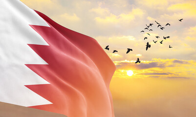 Waving flag of Bahrain against the background of a sunset or sunrise. Bahrain flag for Independence...