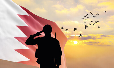 Silhouette of a soldier with the Bahrain flag stands against the background of a sunset or sunrise....