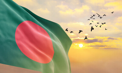Waving flag of Bangladesh against the background of a sunset or sunrise. Bangladesh flag for...