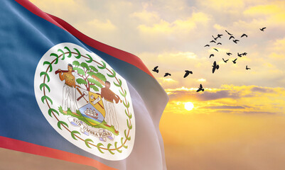 Waving flag of Belize against the background of a sunset or sunrise. Belize flag for Independence...