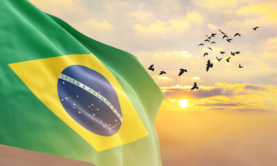 Waving flag of Brazil against the background of a sunset or sunrise. Brazil flag for Independence...