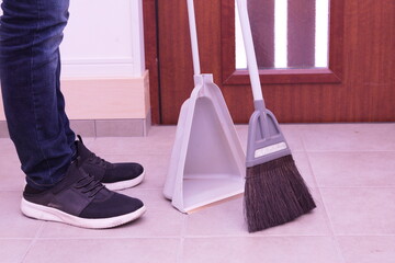 玄関内にてほうきで掃除するアップ写真。ゴミ取り、掃除、清潔感、家事、管理をイメージ