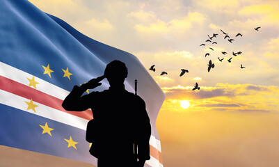 Silhouette of a soldier with the Cabo Verde flag stands against the background of a sunset or...