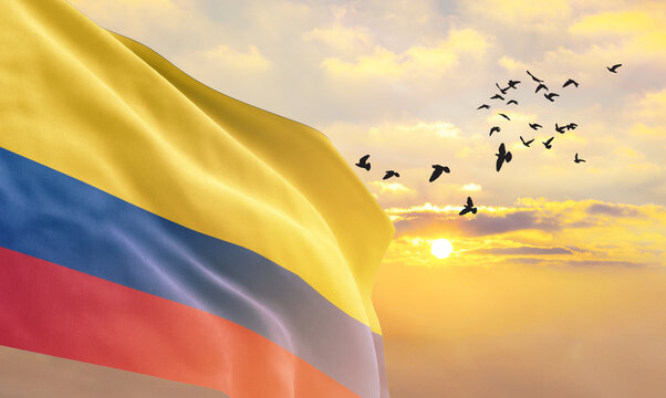 Waving flag of Colombia against the background of a sunset or sunrise. Colombia flag for Independence Day. The symbol of the state on wavy fabric.