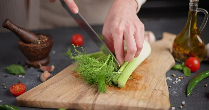 Woman cutting fennel greens on wooden cutting board
