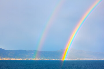 Rainbow over the sea on a background of mountains and blue sky