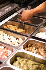 Man scooping Gelato in the showcase at the Gelato shop. Colourful and tasty Gelato. Various of ice cream flavors.