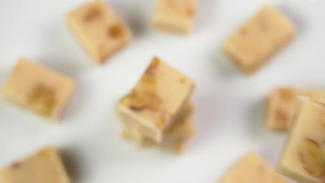 Sliced Spanish Christmas Turron on a white background. Hand taking single sweet slice close up