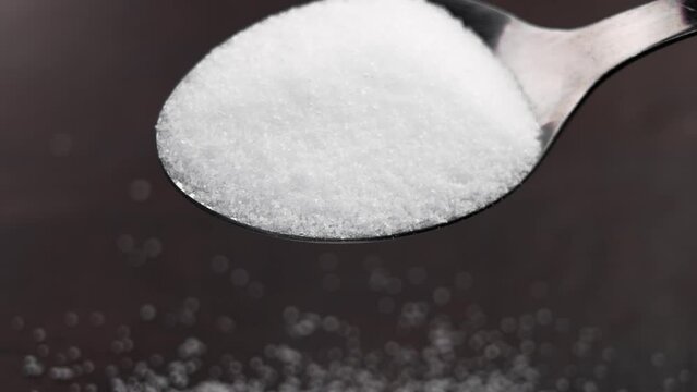 Stevia sugar substitute powder in teaspoon close up. Sprinkling in slow motion