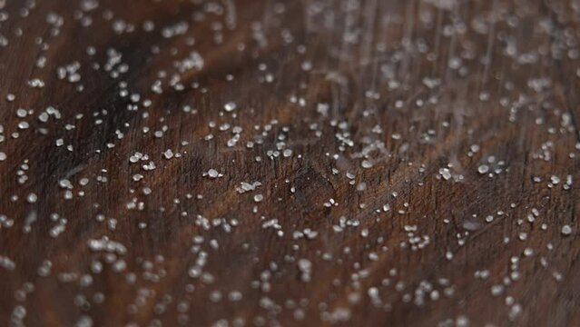 Stevia sugar substitute crystals falling in slow motion into a wooden bowl close up. Rotation