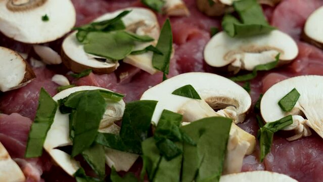 Sprinkling chopped fresh green spinach over pork and sliced portobello mushrooms. Mediterranean cuisine concept
