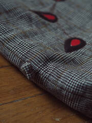 Vertical straight from above shot of a woman&rsquo;s plaid shoulder bag detail on parquet floor.