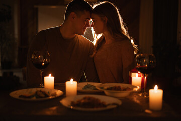 Silhouette of happy couple in love celebrating Valentines day dining at home, having date with candles. Valentines day celebration
