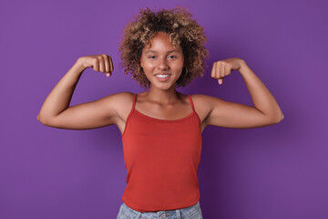 Young strong smiling African American woman teenager looks at screen with smile posing in strongman...