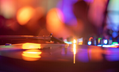 Vinyl record, turntable, disco blurry lights as background. Different colors.
