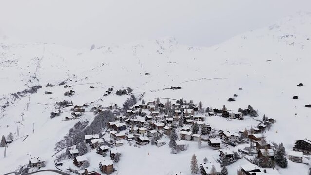 Snowy winter scene of Swiss town Arosa. Drone flight over snow-covered homes. 