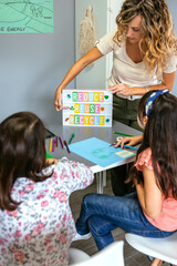 Female teacher explaining to students in classroom how it is a ecologic process while pointing to lightbox with text reduce, reuse, recycle. Sustainable lifestyle education concept.