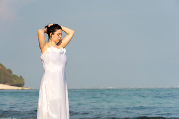 Fototapeta na wymiar Portrait of a beautiful young woman in white dress on the beach