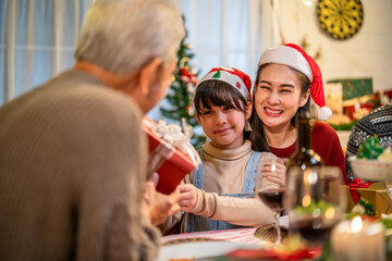 Obraz na płótnie Canvas Asian family giving gift box to young daughter during Christmas party. 