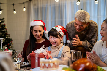 Asian family giving gift box to young daughter during Christmas party. 