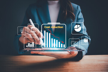 Businesswoman pointing down arrow of the graph with cost reduction business finance on virtual screen. Business, technology, cost management, cut budget, cost reduction concept. - obrazy, fototapety, plakaty