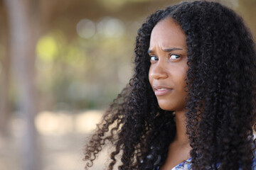 Upset black woman looking at camera in a park - obrazy, fototapety, plakaty