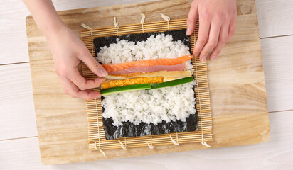 Makizushi, Sushi rolls, Rolled sushi. A woman making sushi rolls. Ehomaki, seafood rolls, Setsubun,...