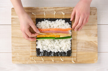 Makizushi, Sushi rolls, Rolled sushi. A woman making sushi rolls. Ehomaki, seafood rolls, Setsubun, etc.　巻き寿司。巻き寿司を作る女性。恵方巻、海鮮巻き、節分など © Kana Design Image