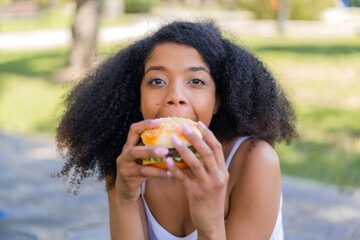 Young African American woman at outdoors holding a burger
