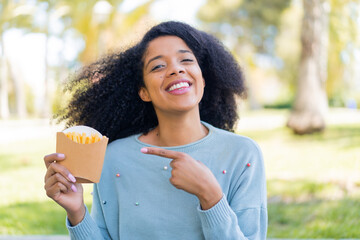 Young African American woman holding fried chips at outdoors and pointing it