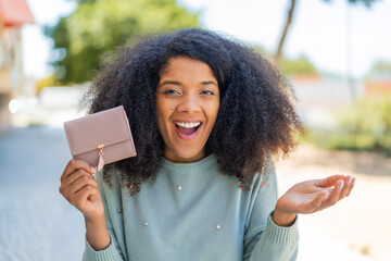 Young African American woman holding a wallet at outdoors with shocked facial expression